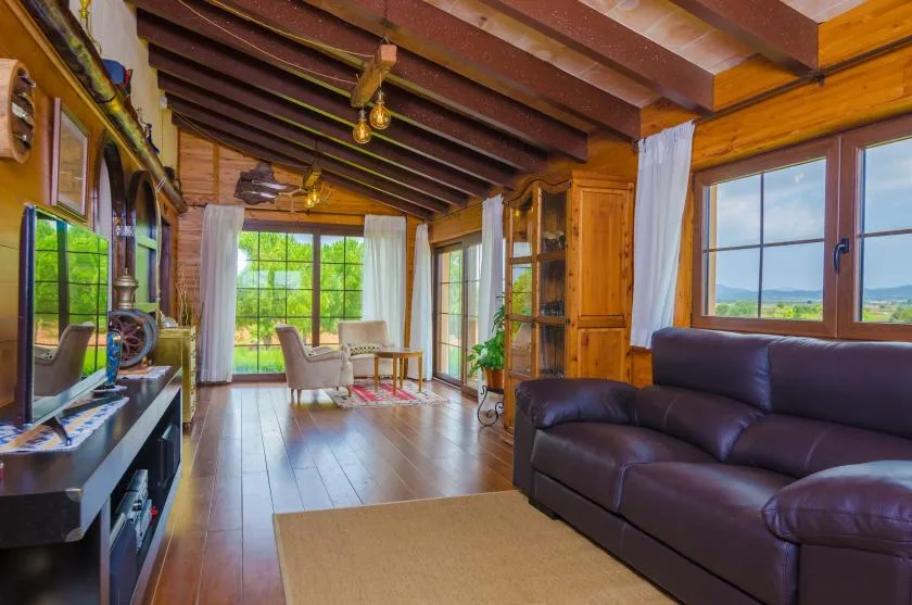 Una sala de estar con paneles de madera, asientos oscuros y ventanas grandes.