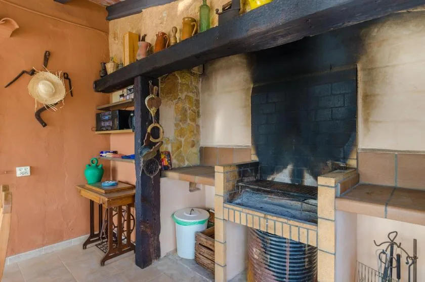 Una zona rústica de chimenea interior con un amplio hogar y una viga de madera oscura.