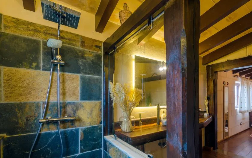Un baño con azulejos, una zona de ducha de vidrio y un mueble de madera.