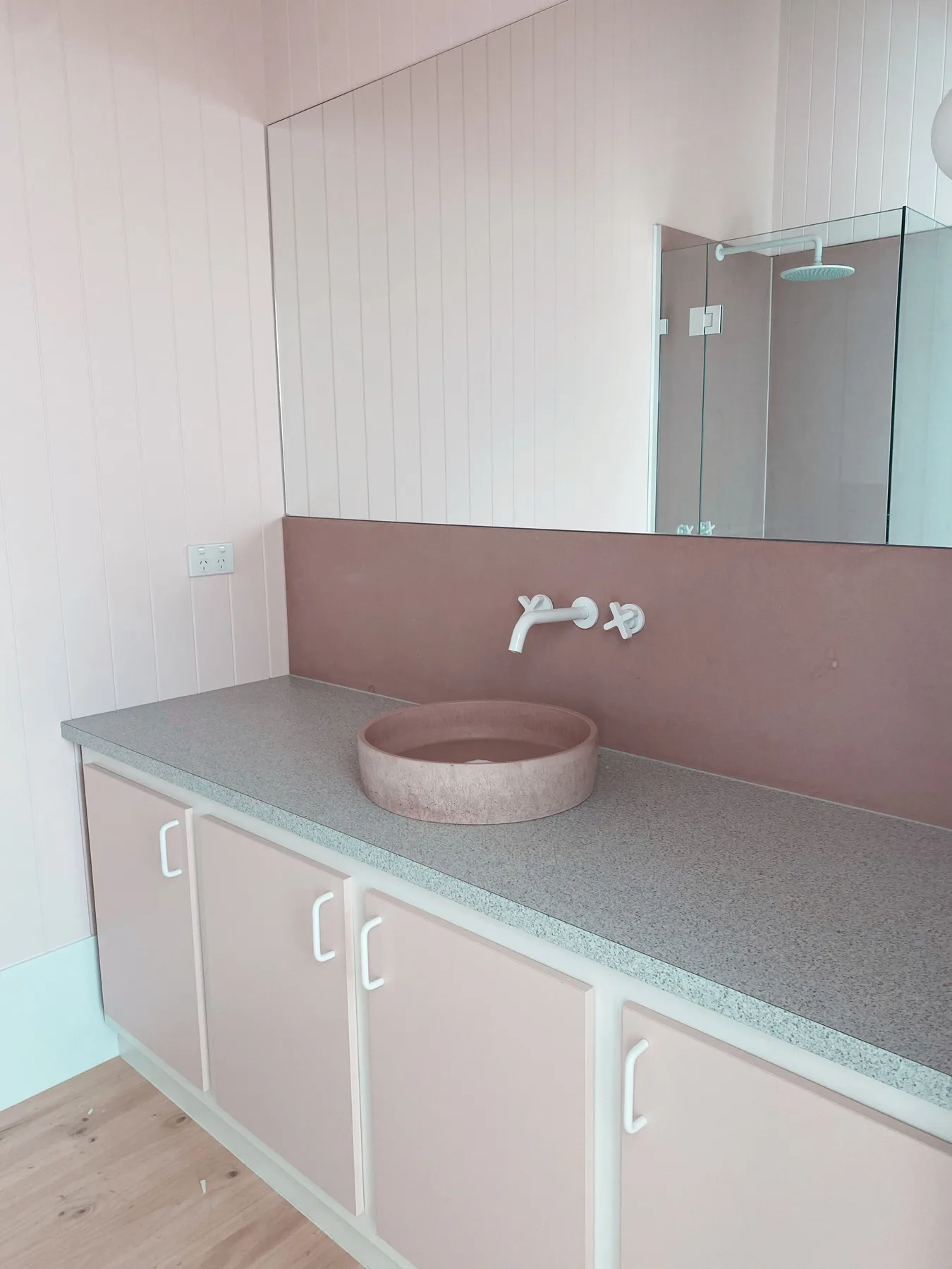 Un tocador de baño con lavabo, grifo de pared y espejo.