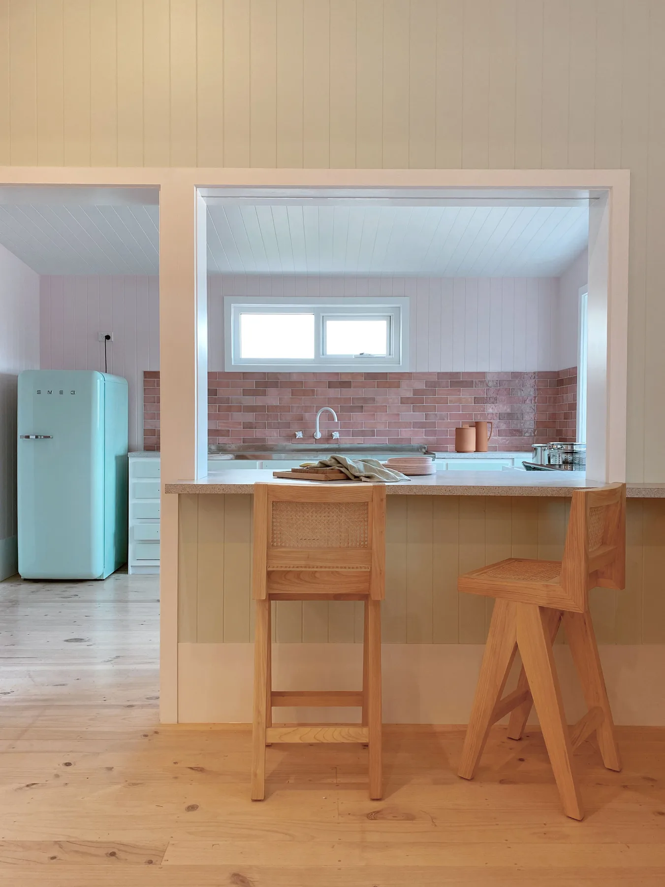 Cocina con una barra de madera y taburetes, vista a través de una abertura.