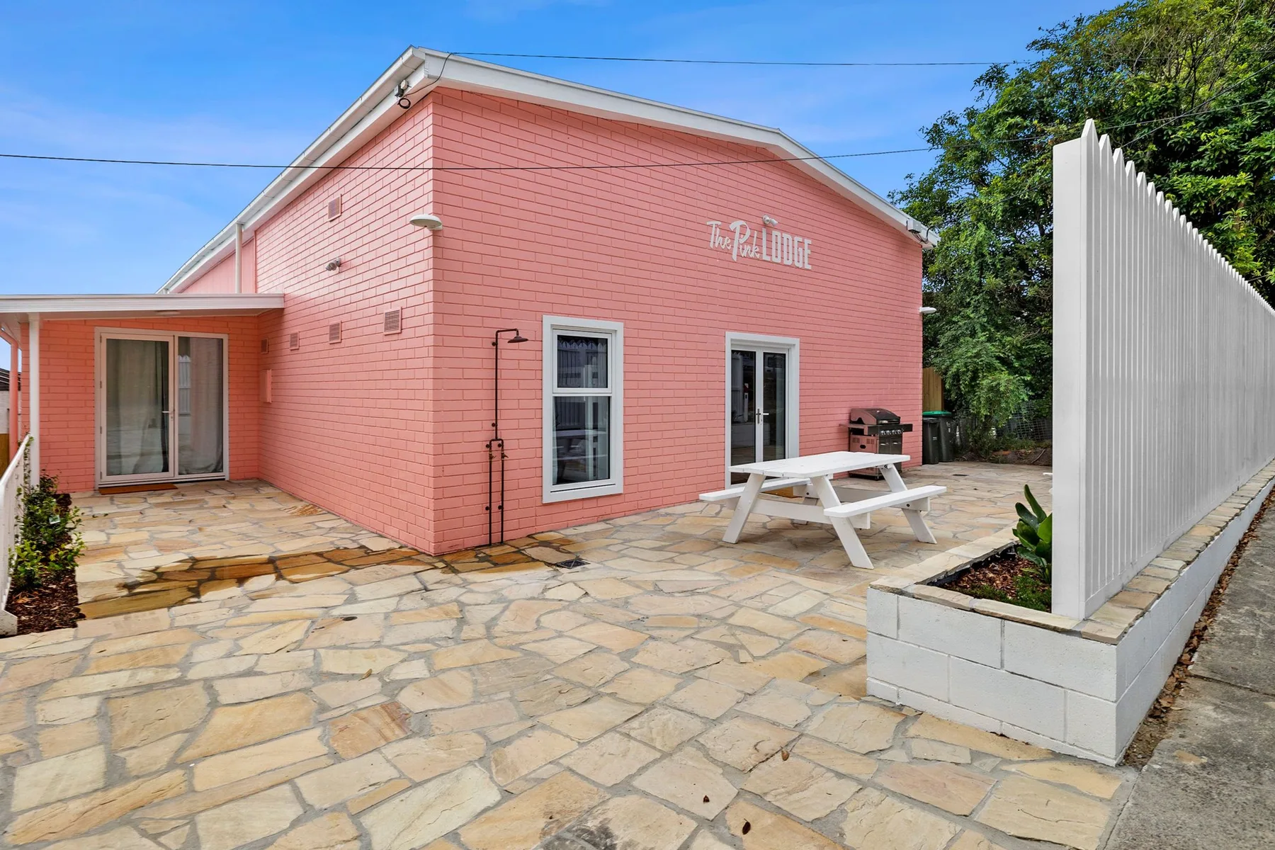 Edificio rosa con un patio pavimentado y una mesa de picnic al aire libre.