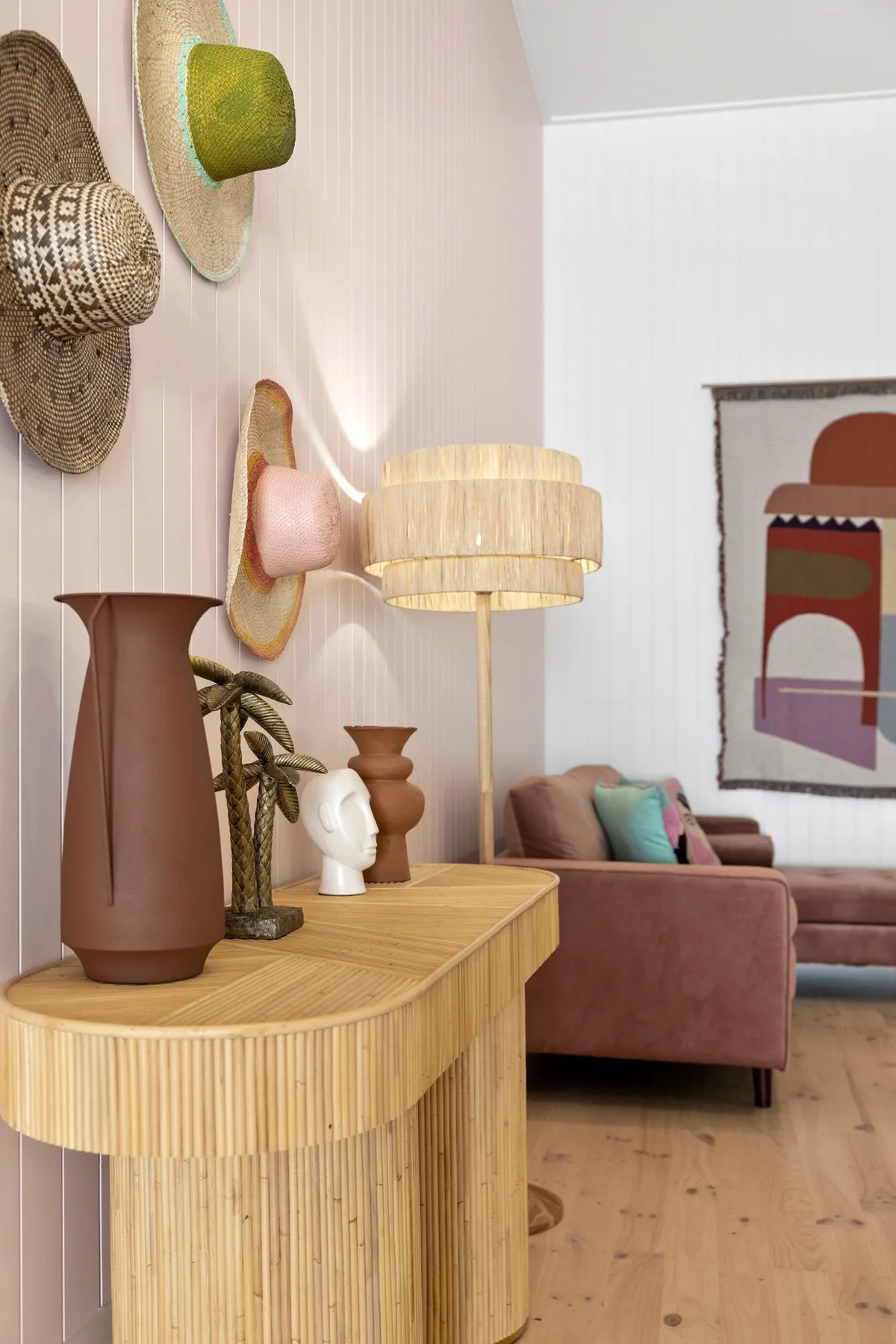 Una sala de estar con un sofá rosa y una mesa consola junto a él.