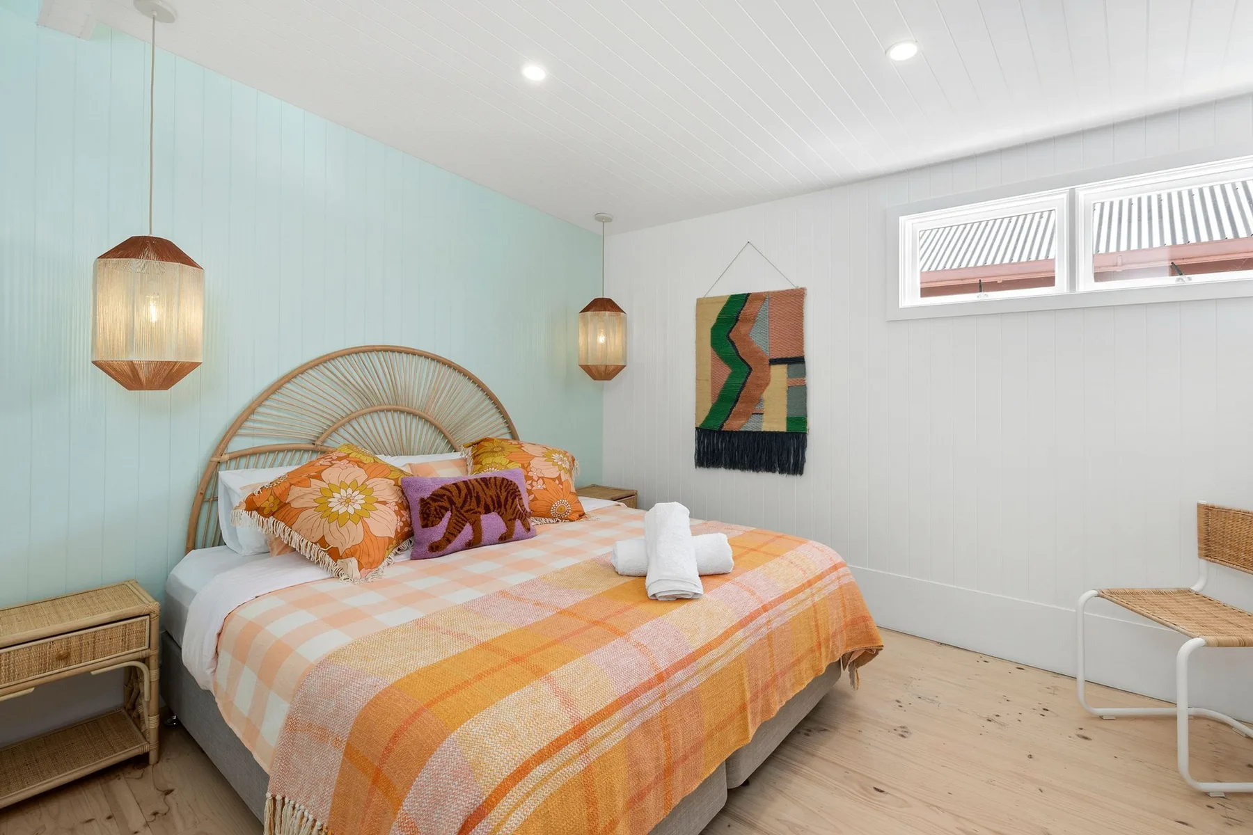 Dormitorio con una cama cubierta con una manta de cuadros coloridos.
