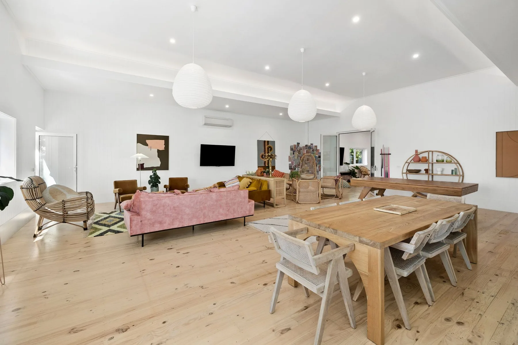 Una luminosa sala de estar y comedor con un sofá rosa y una mesa de madera.