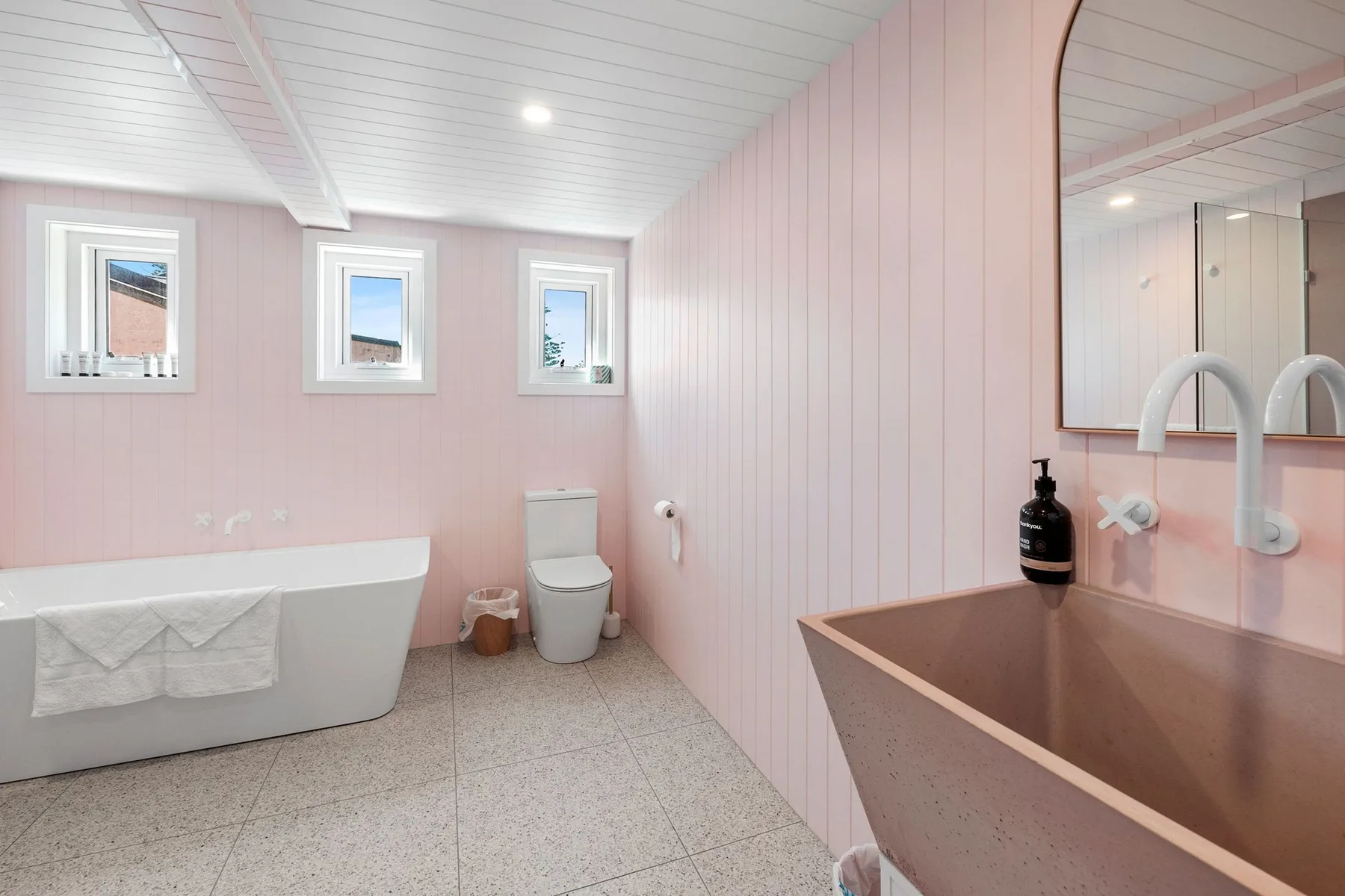 Un baño rosa con una bañera y un lavabo separado.