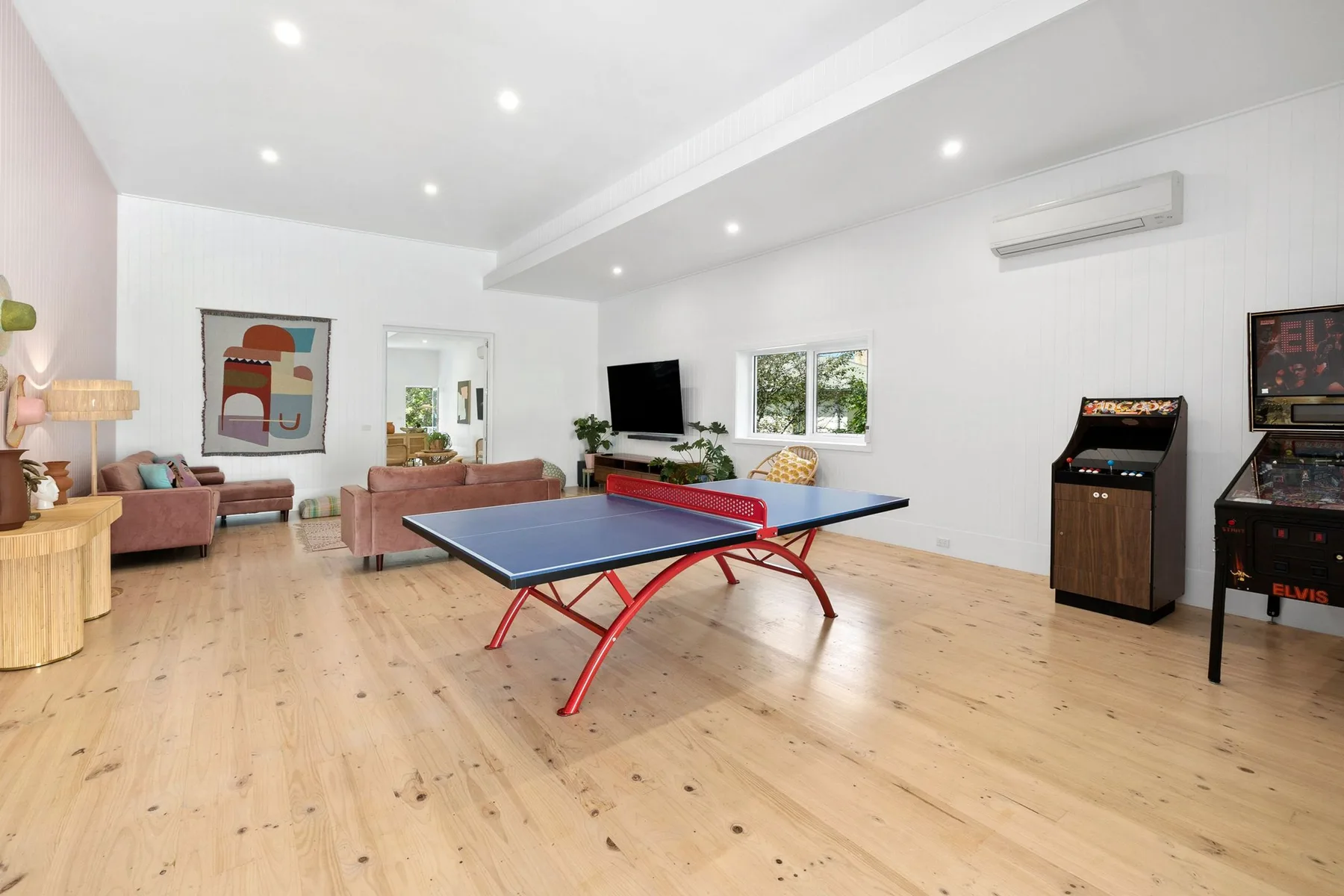 Una sala de juegos luminosa con una mesa de ping-pong y juegos arcade.
