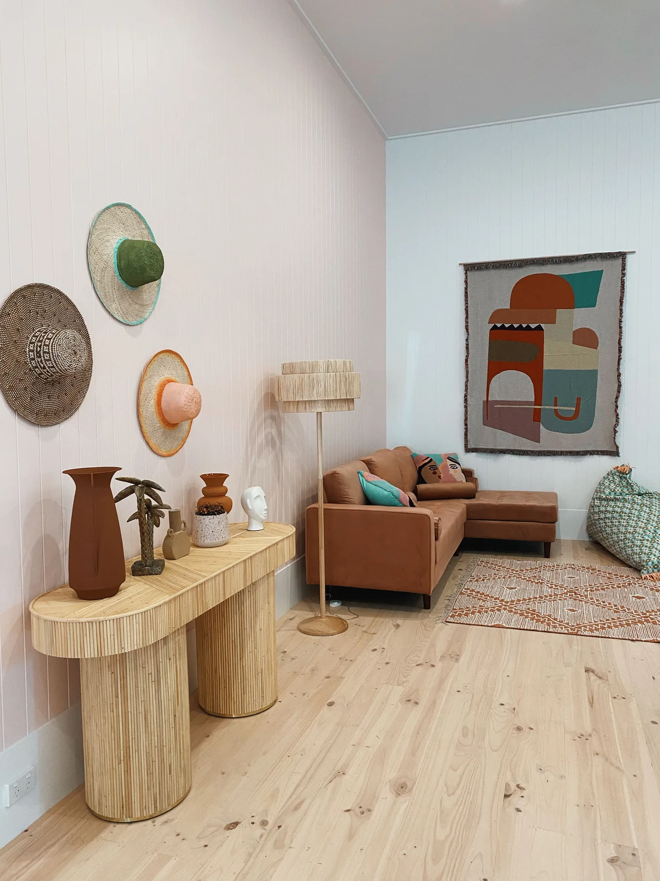 Una sala de estar con asientos marrones, arte mural y una alfombra tejida.