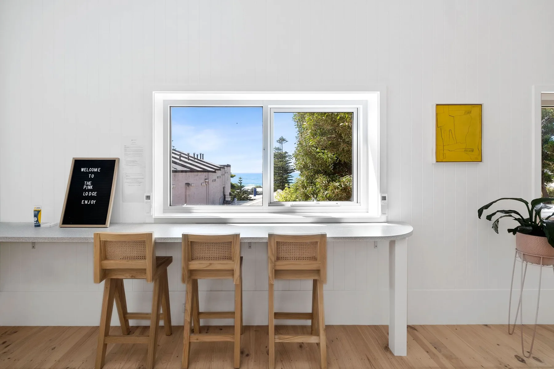 Una habitación luminosa con una barra larga y asientos de madera bajo las ventanas.