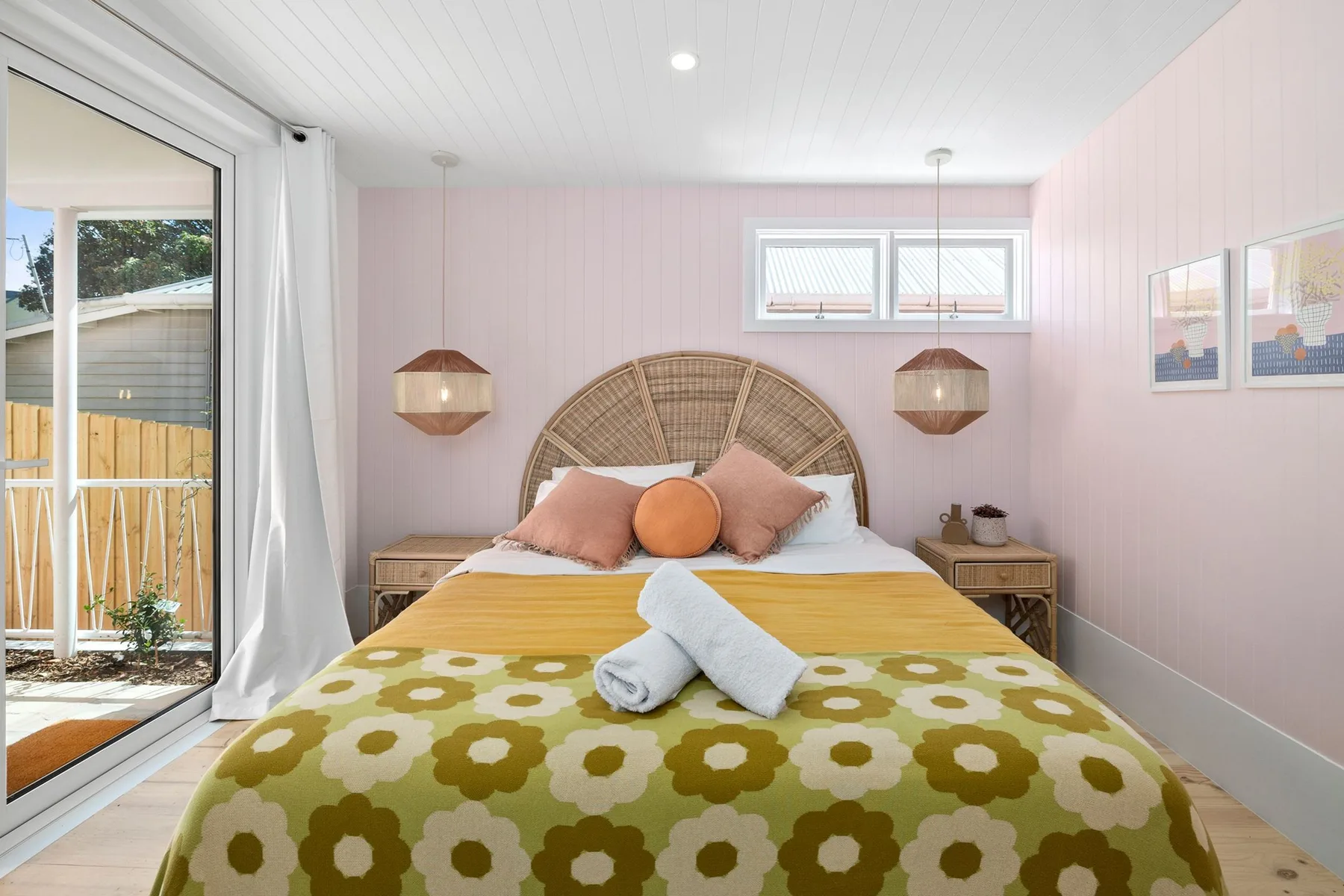 Dormitorio rosa con una cama doble y puertas de vidrio que dan a un balcón.