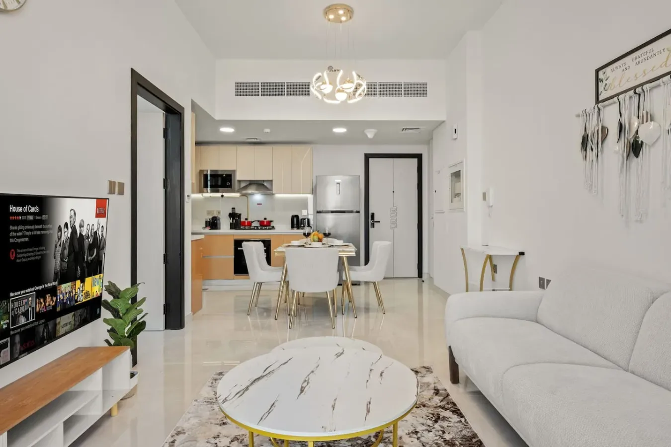 A bright living room opens onto a compact kitchen, with a dining table between them.