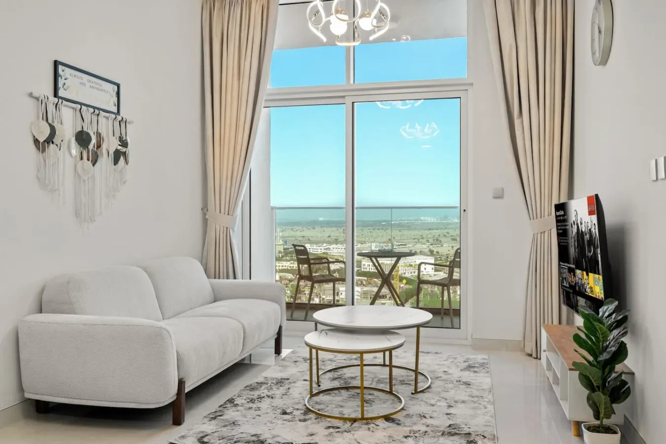 A bright living room with seating, round tables, and glass doors opening to a balcony view.