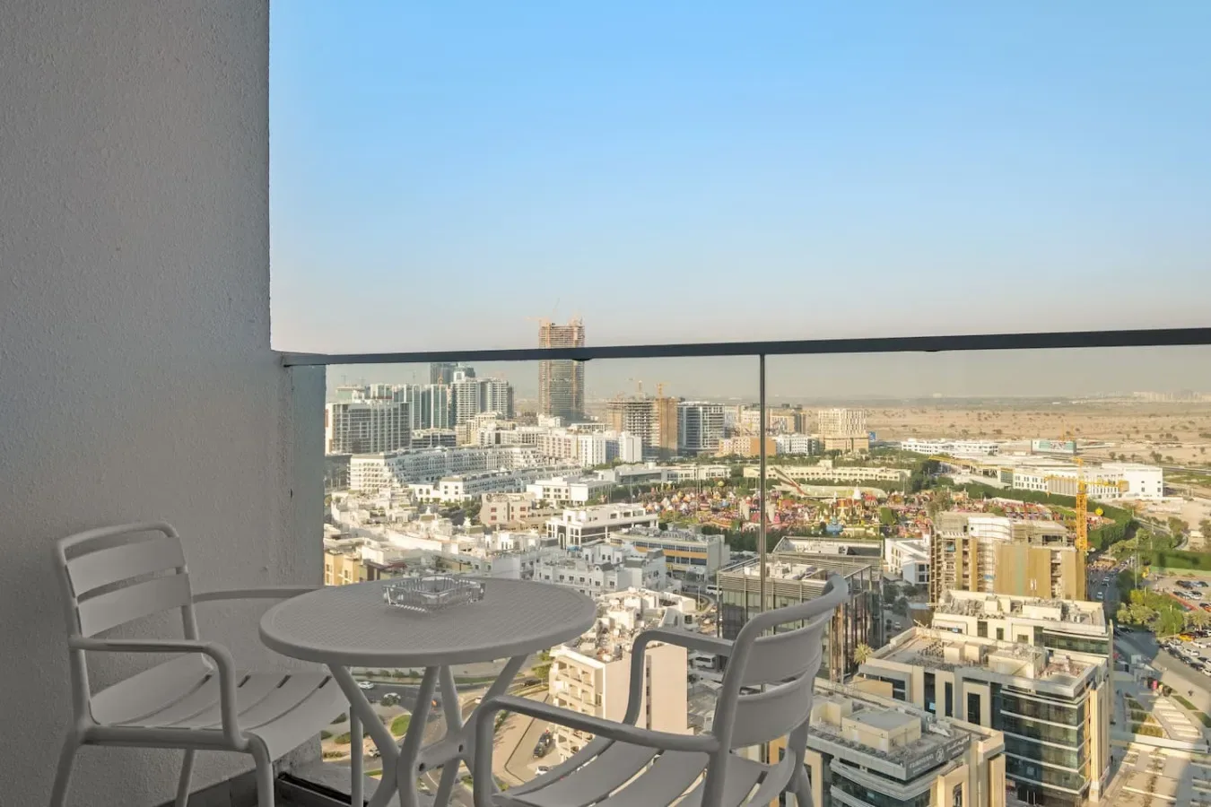 A balcony seating area overlooks a city skyline beneath a clear sky.