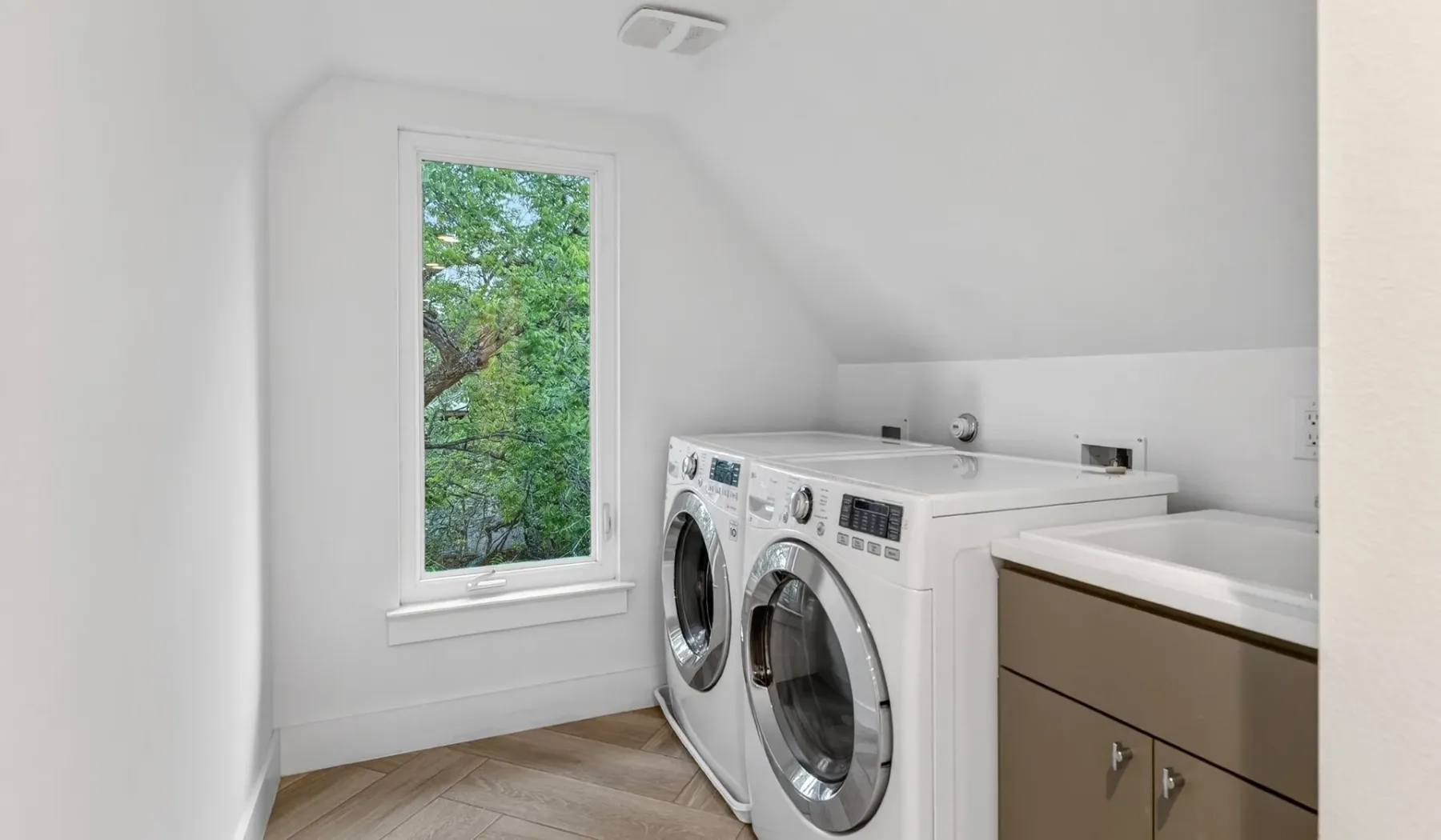 A laundry room with a washer and dryer beside a window.