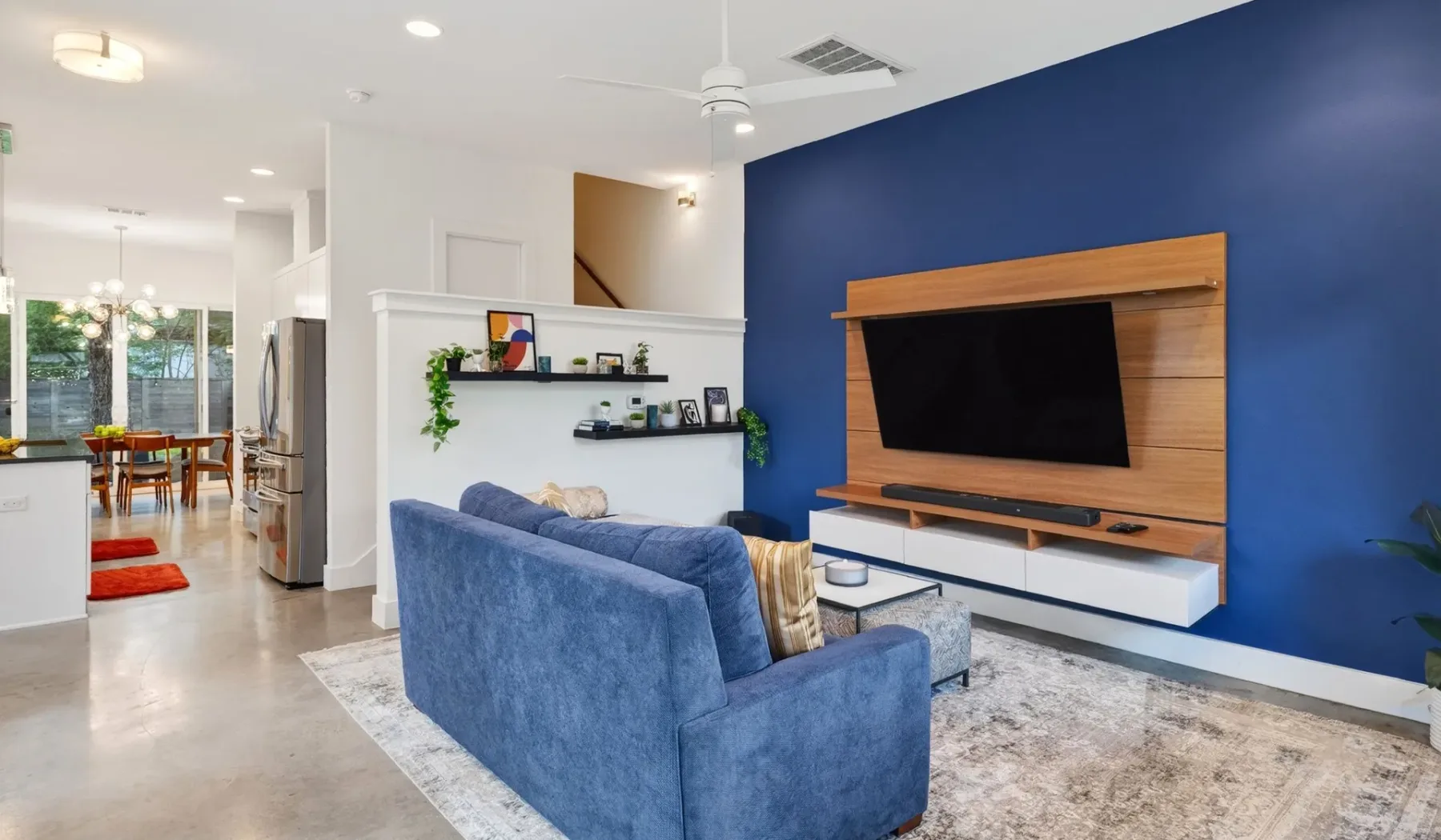 Living room with blue seating facing a wall-mounted television.