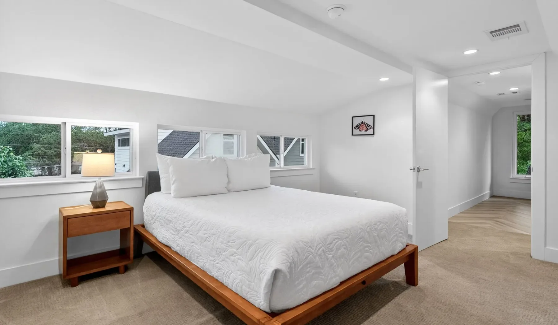 A bright bedroom with a bed beside several windows.