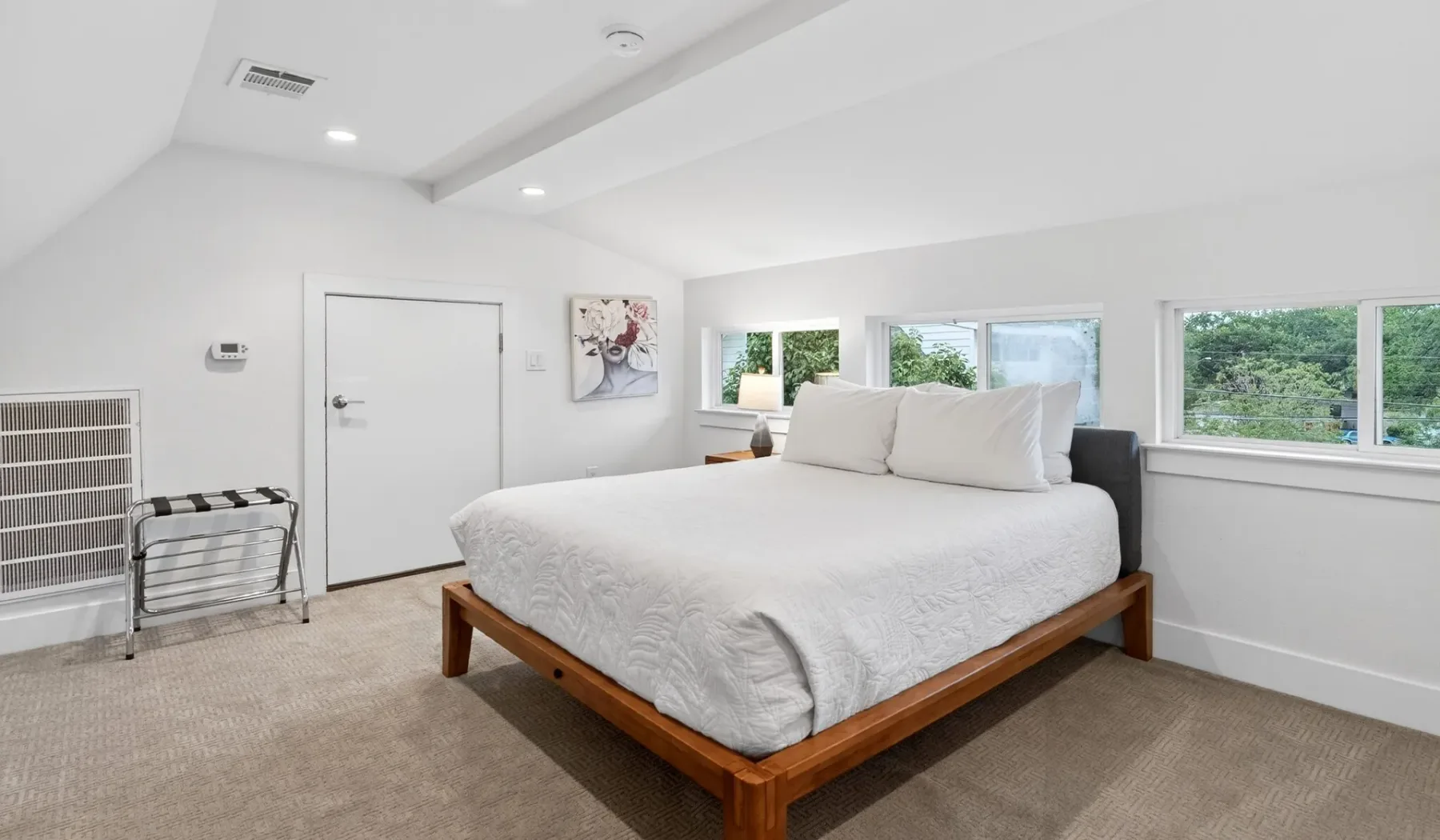 A bright bedroom with a large bed beside wide windows.