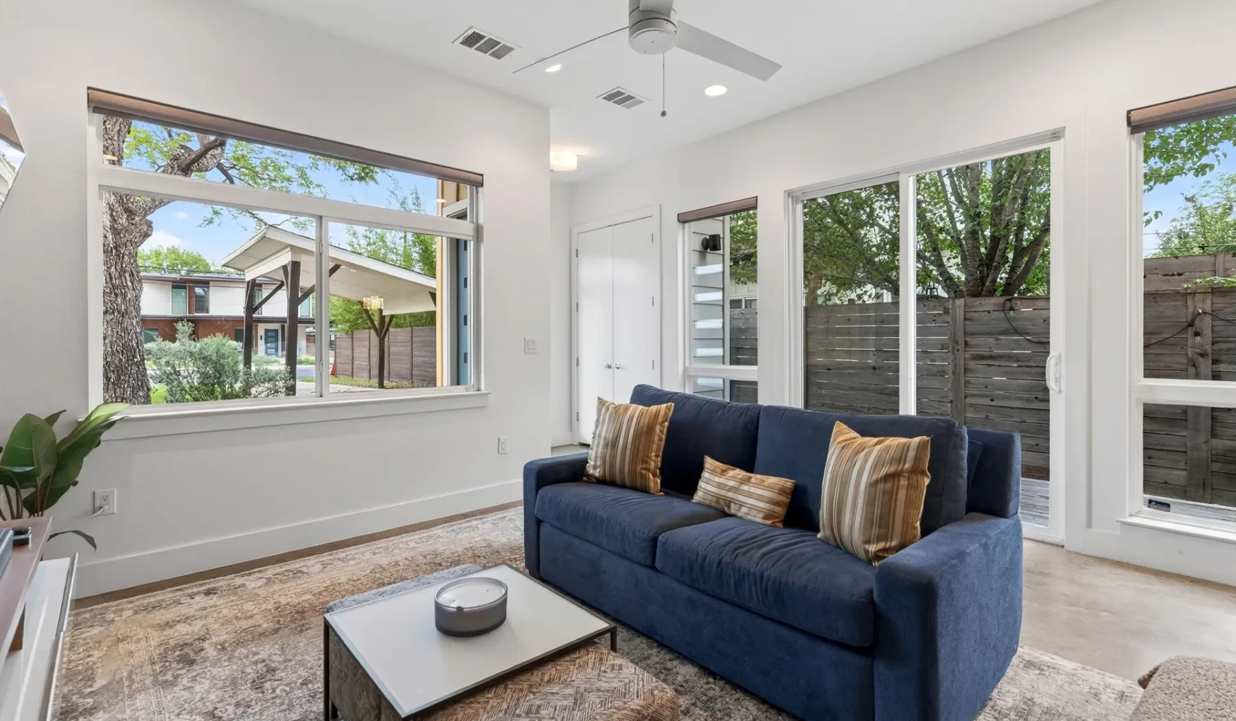 A bright living room with a blue sofa beside large windows.