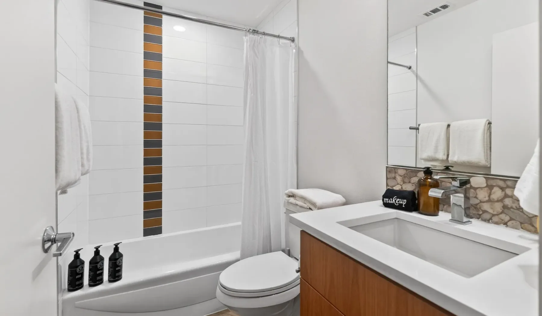 A tiled bathroom with a bathtub, shower curtain, and vanity.