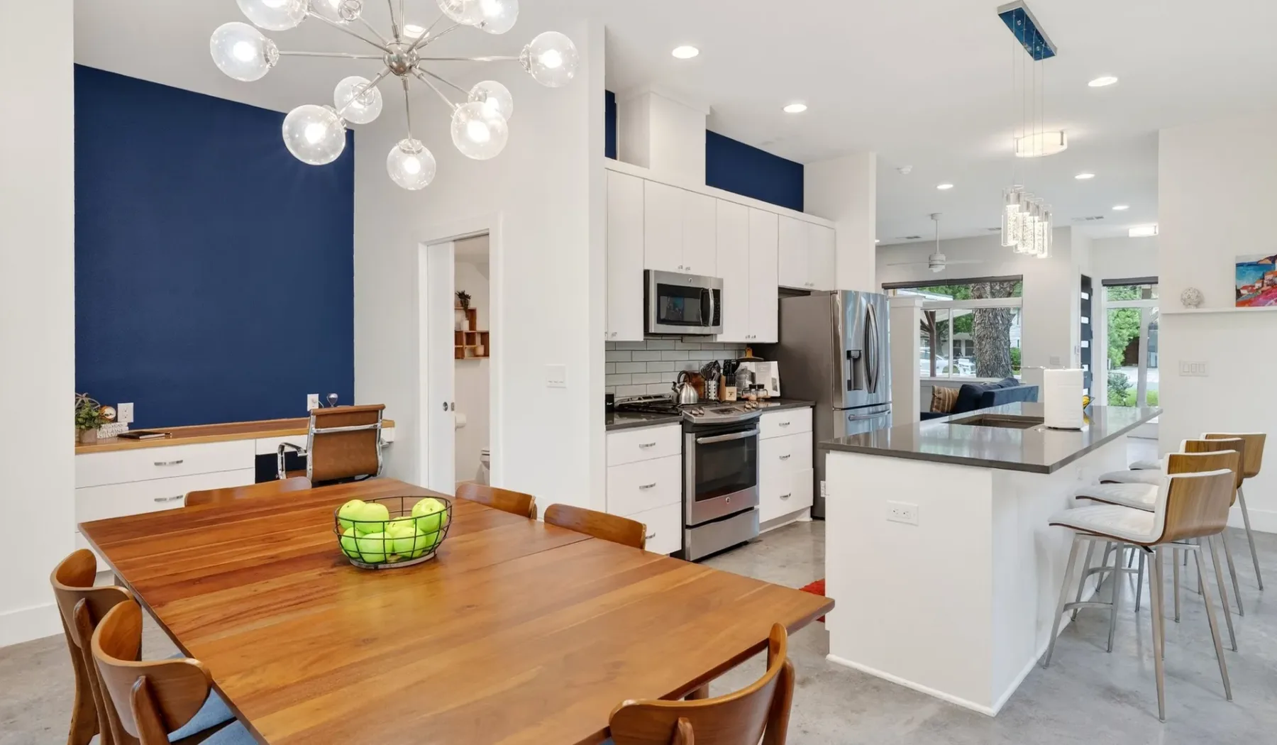 An open kitchen and dining area with a wooden table and counter seating.