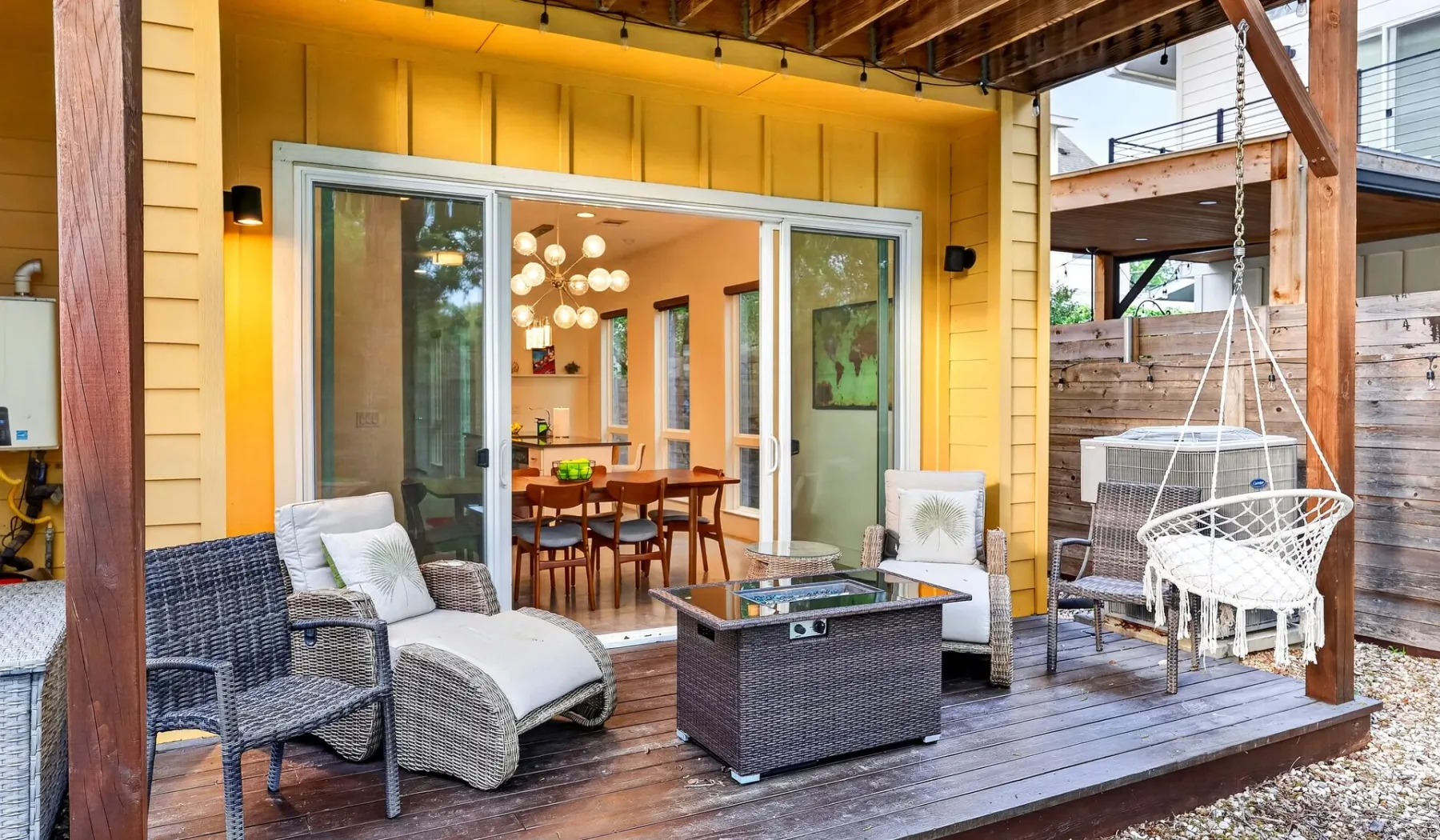 A covered wooden deck with outdoor seating opens onto a bright dining area.