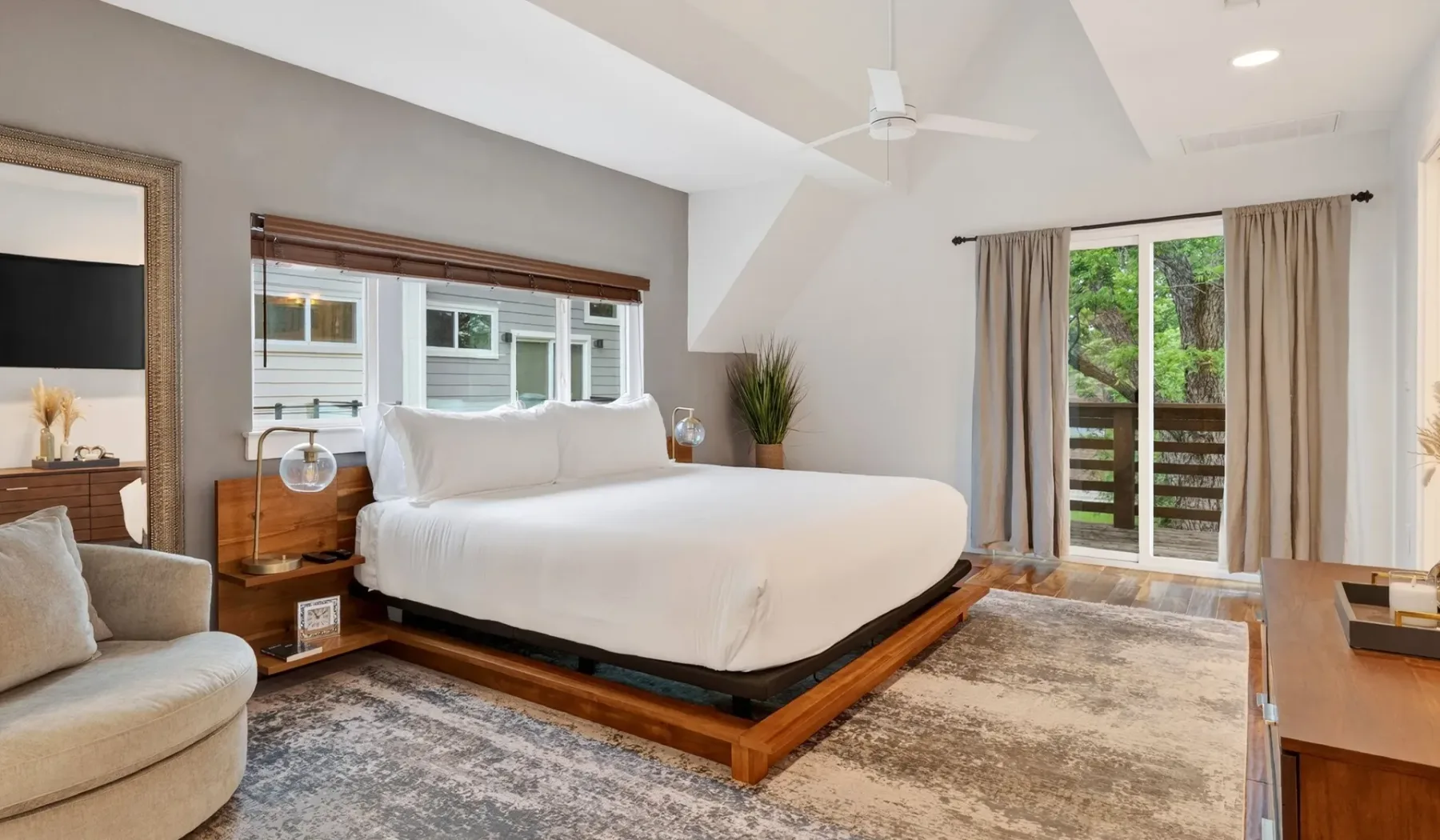 A bedroom with a large bed, bedside tables, and sliding glass doors opening to a balcony.