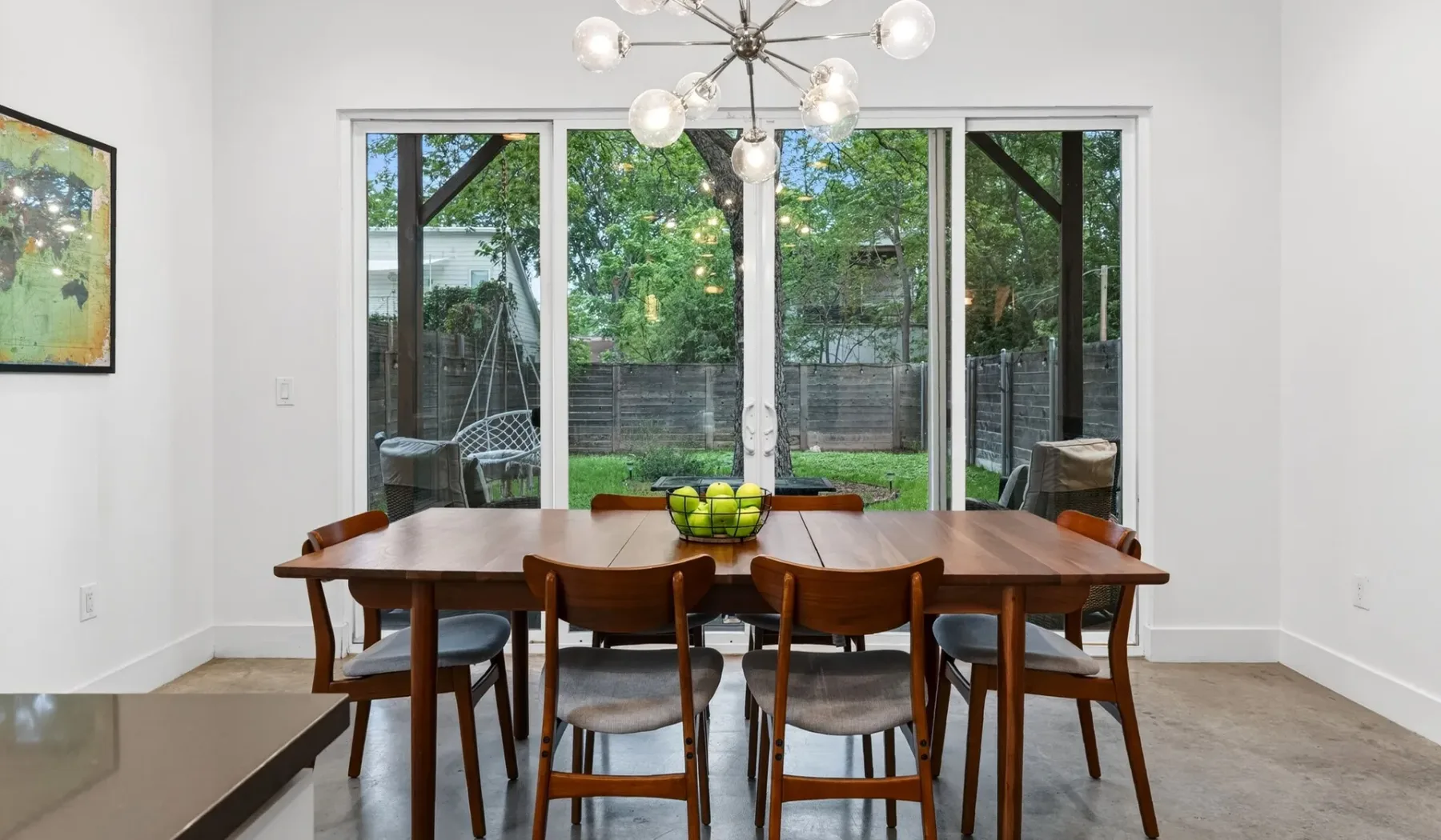 A dining area with a wooden table and chairs in front of large windows.