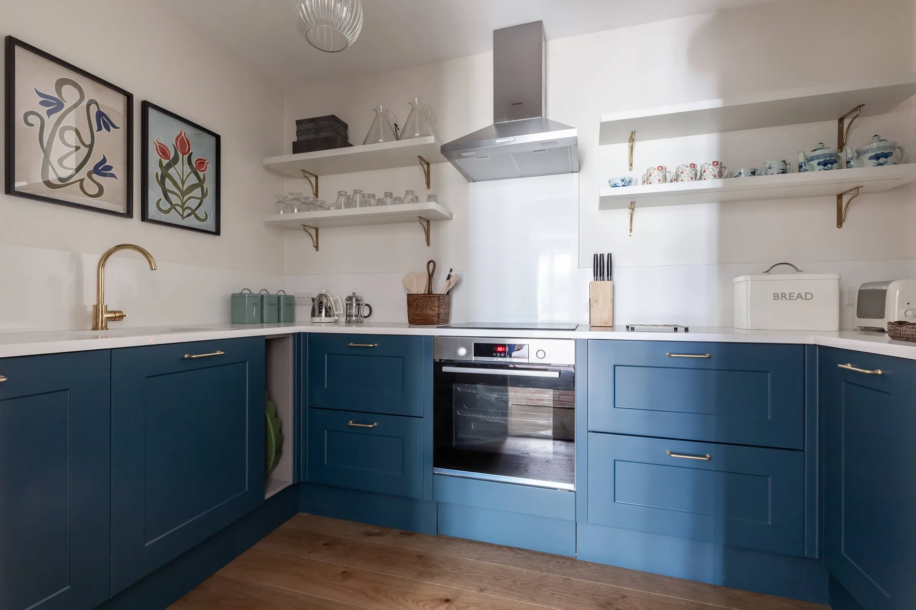 A bright kitchen with blue cabinets, a countertop, and a built-in oven.