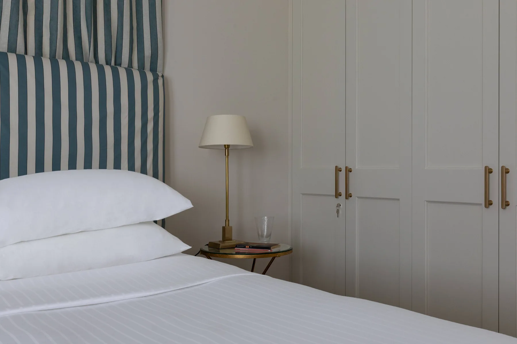 A bedroom with a neatly made bed beside built-in wardrobes.
