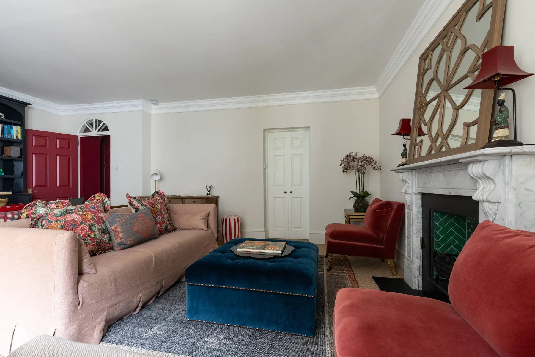 A living room with seating around a blue ottoman and a fireplace.