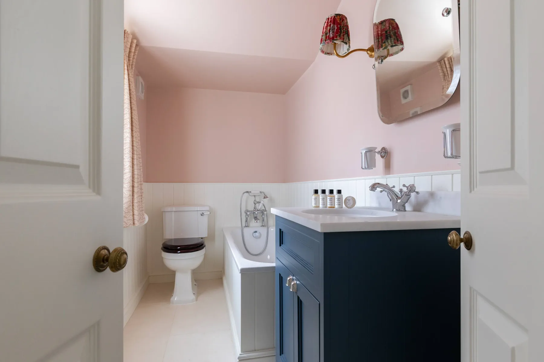 A bathroom with a bathtub, toilet, and dark vanity.
