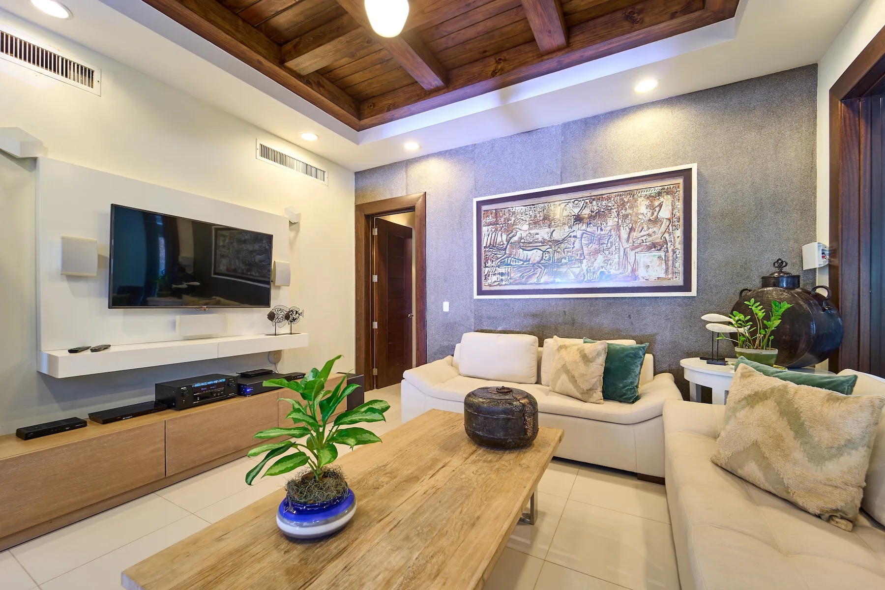 Una sala de estar con televisor, asientos y una mesa de centro de madera.