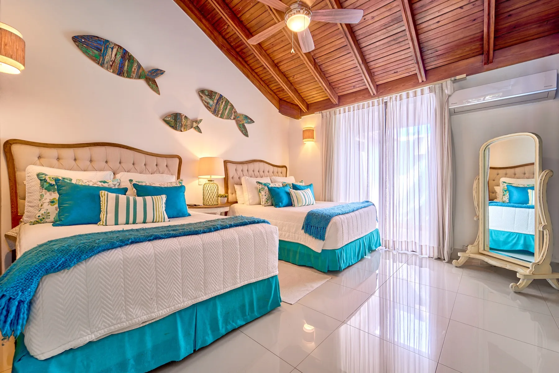 Un dormitorio luminoso con dos camas, detalles azules y techo abovedado de madera.
