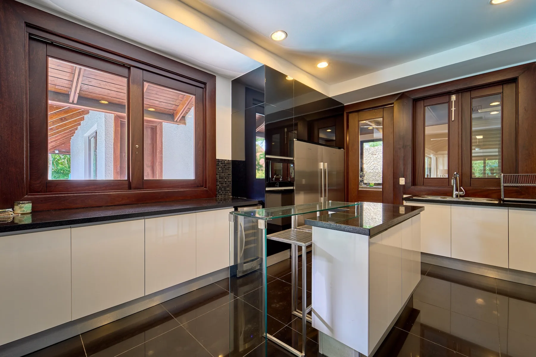 Una cocina moderna con gabinetes oscuros, una isla central y un fregadero bajo la ventana.