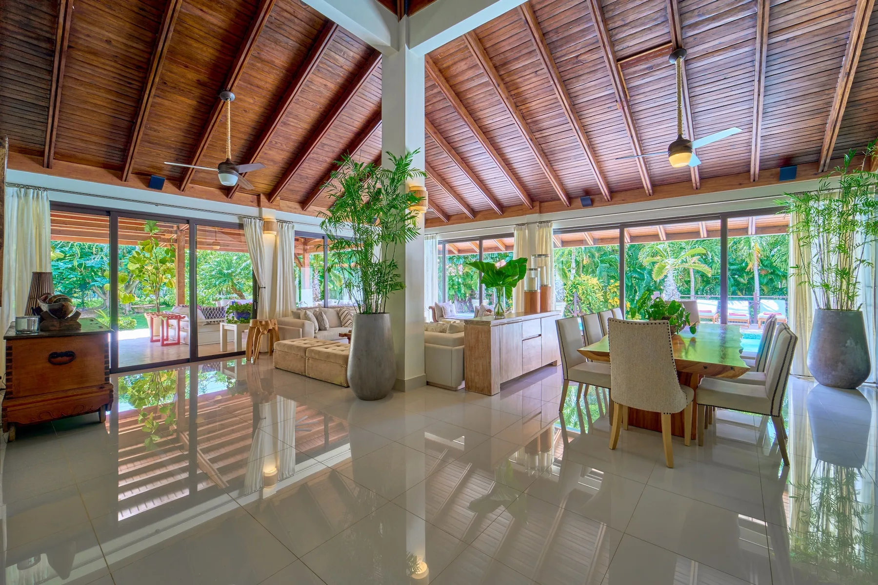 Un luminoso espacio abierto de comedor y sala de estar con grandes ventanas y plantas de interior.