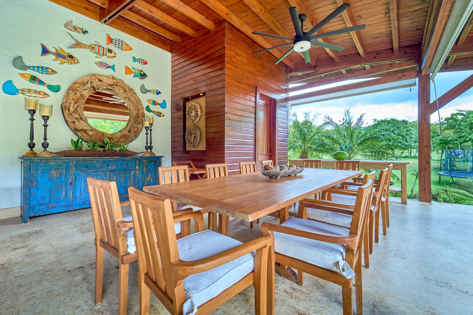 Un comedor exterior cubierto con una mesa larga de madera y sillas.