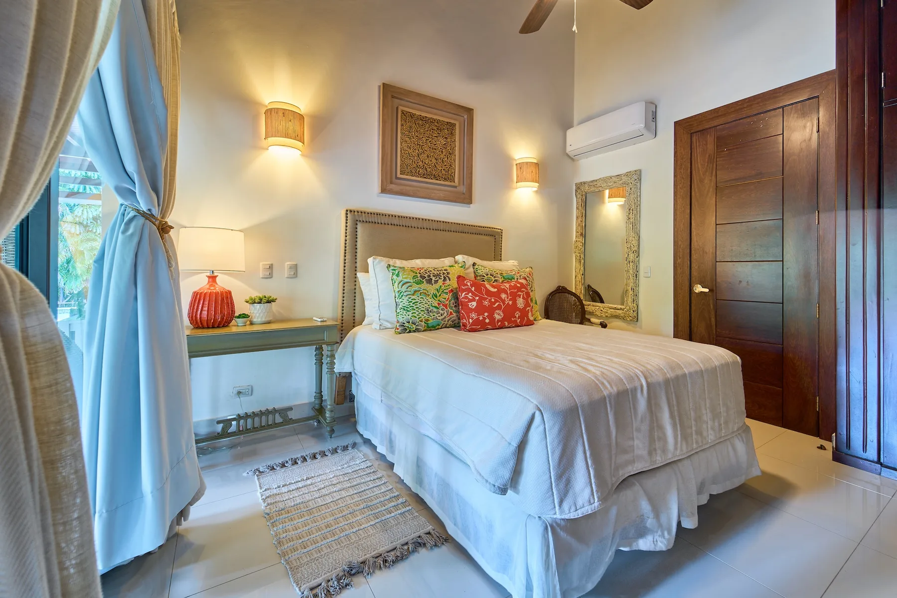 Un dormitorio con una cama grande, una mesa auxiliar y una ventana con cortinas.