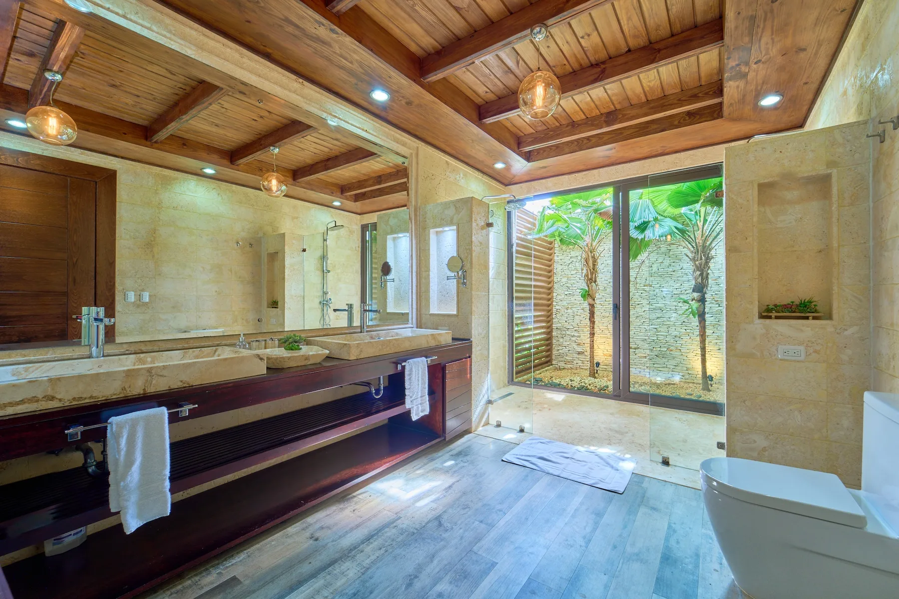 Un baño amplio con un tocador largo y puertas de vidrio que dan a un jardín.