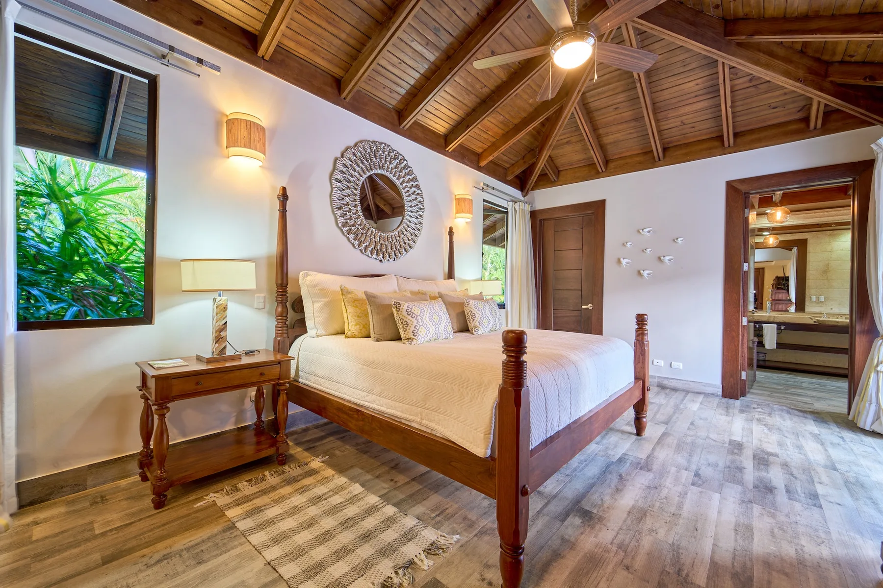 Un dormitorio con una cama de madera, mesitas de noche y un techo alto de madera.