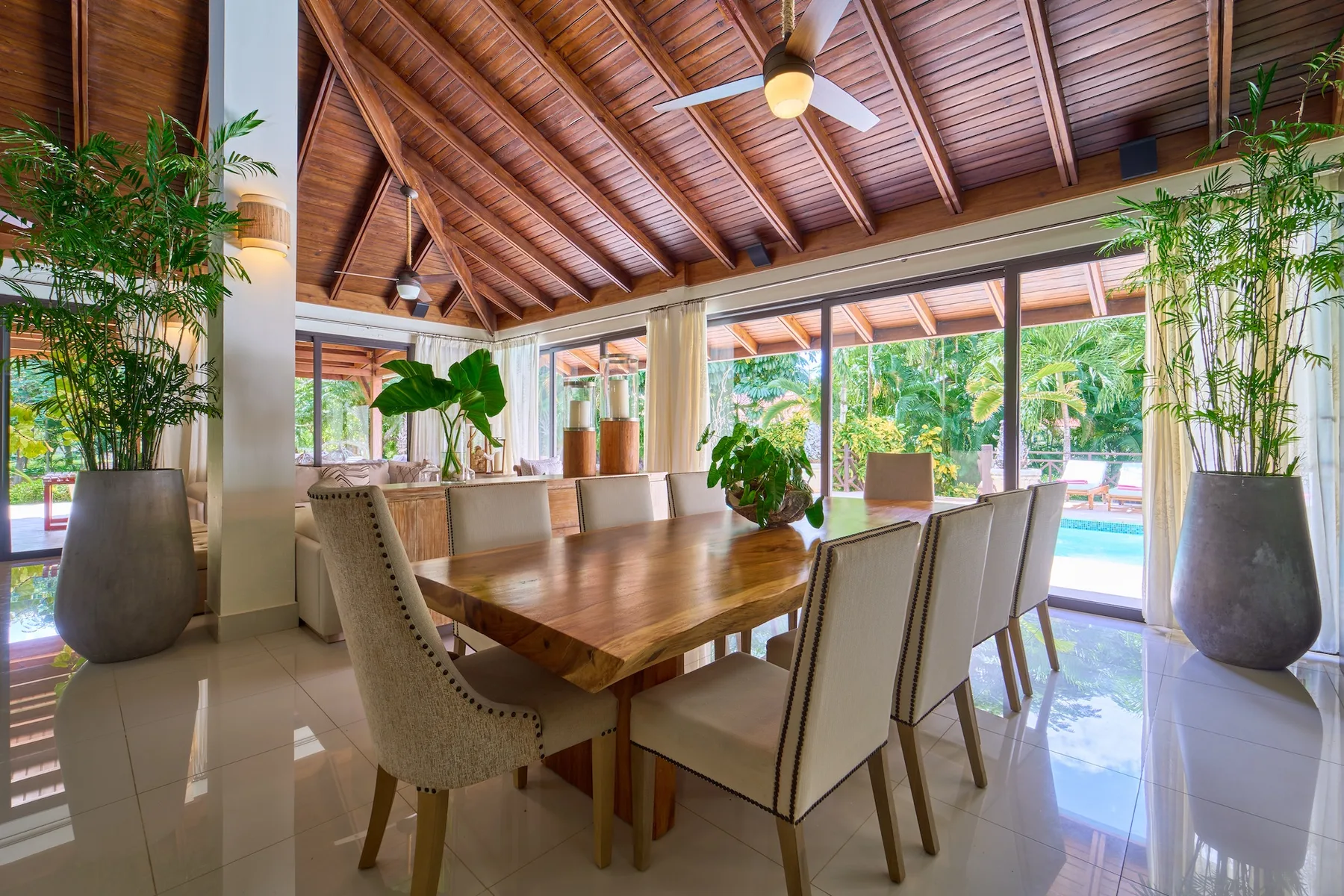 Un comedor luminoso con una larga mesa de madera y grandes ventanales con vistas a la vegetación.