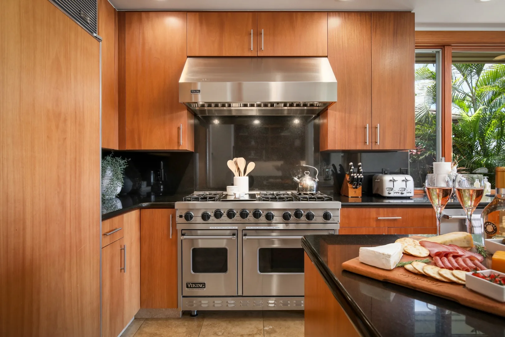 A modern kitchen with a stainless-steel range beneath a large metal hood.