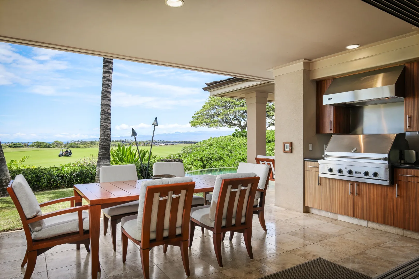 A covered outdoor dining area with a table, seating, and a built-in grill.