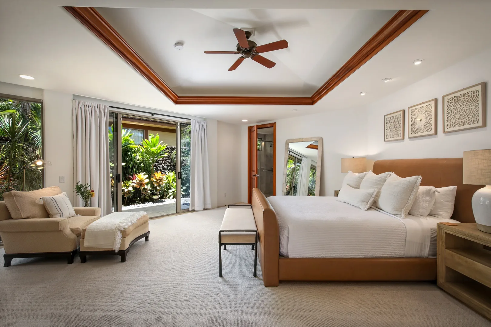 A bright bedroom with a large bed and a seating area beside glass doors.