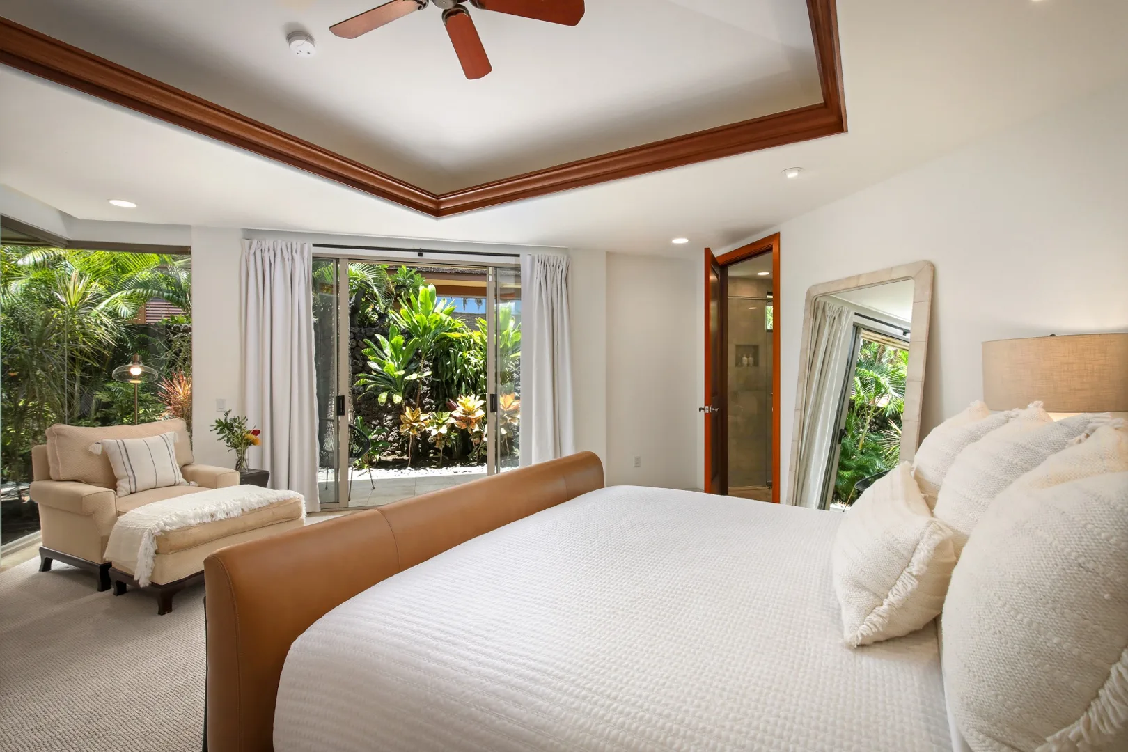 A bright bedroom with a large bed, armchair, and garden-facing windows.