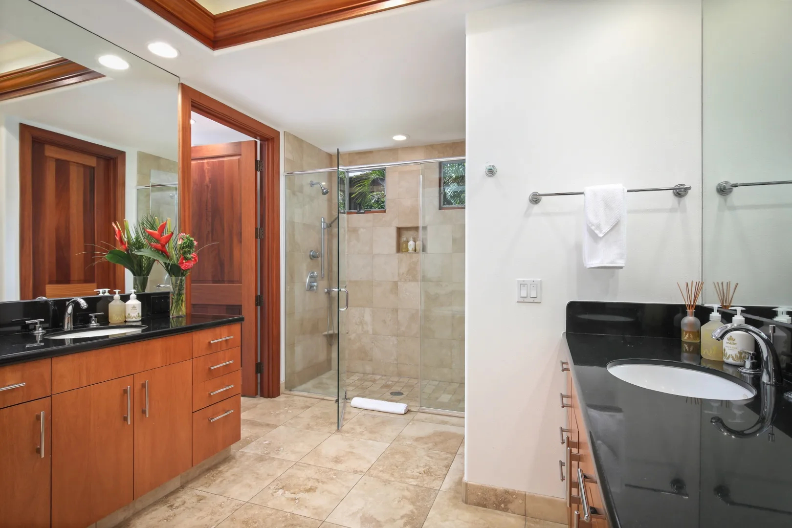 A bathroom with two vanity counters and a glass shower.
