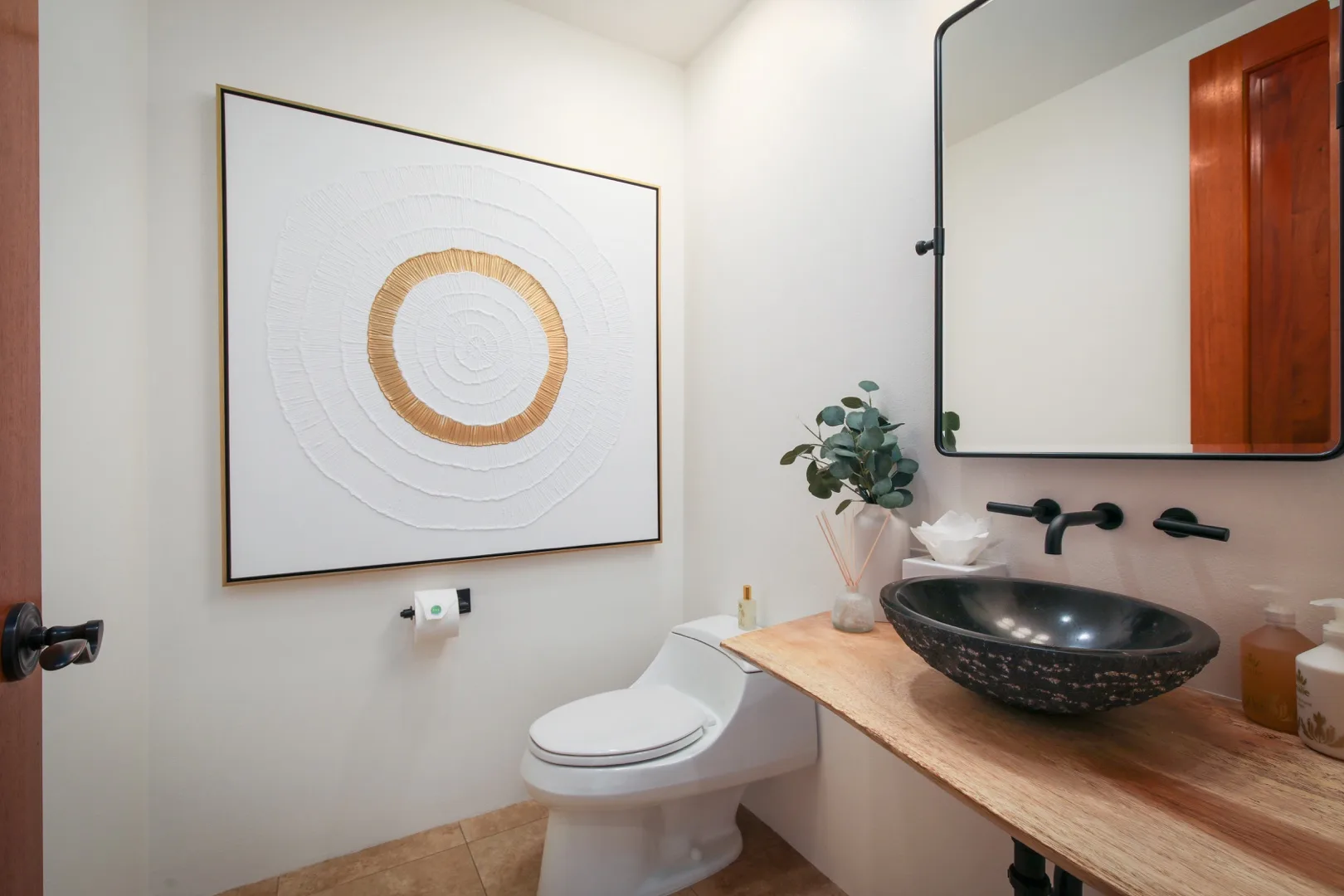 A bathroom with a toilet, wall art, and a countertop basin.