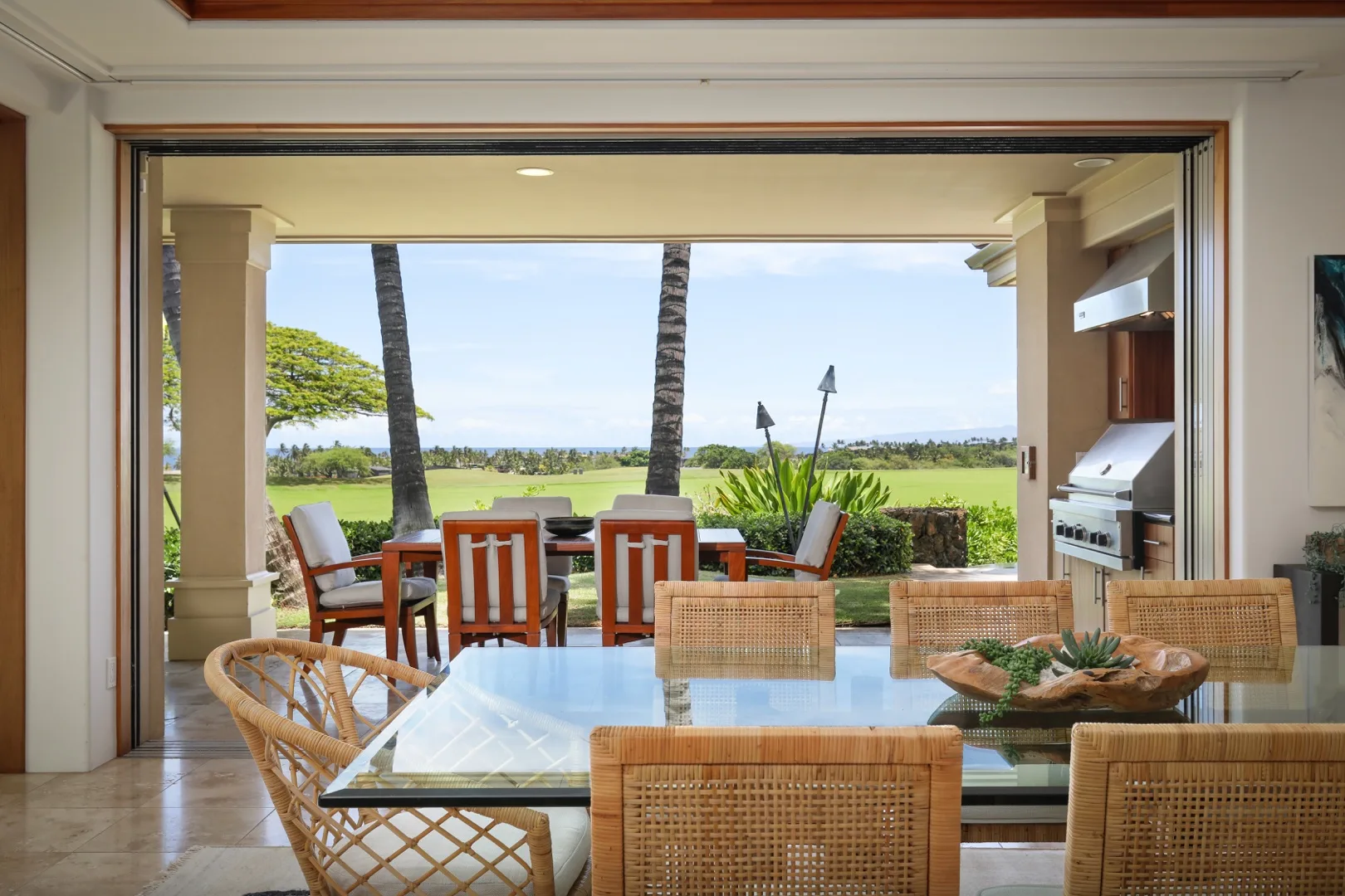 A dining area opens onto an outdoor patio with seating and greenery.