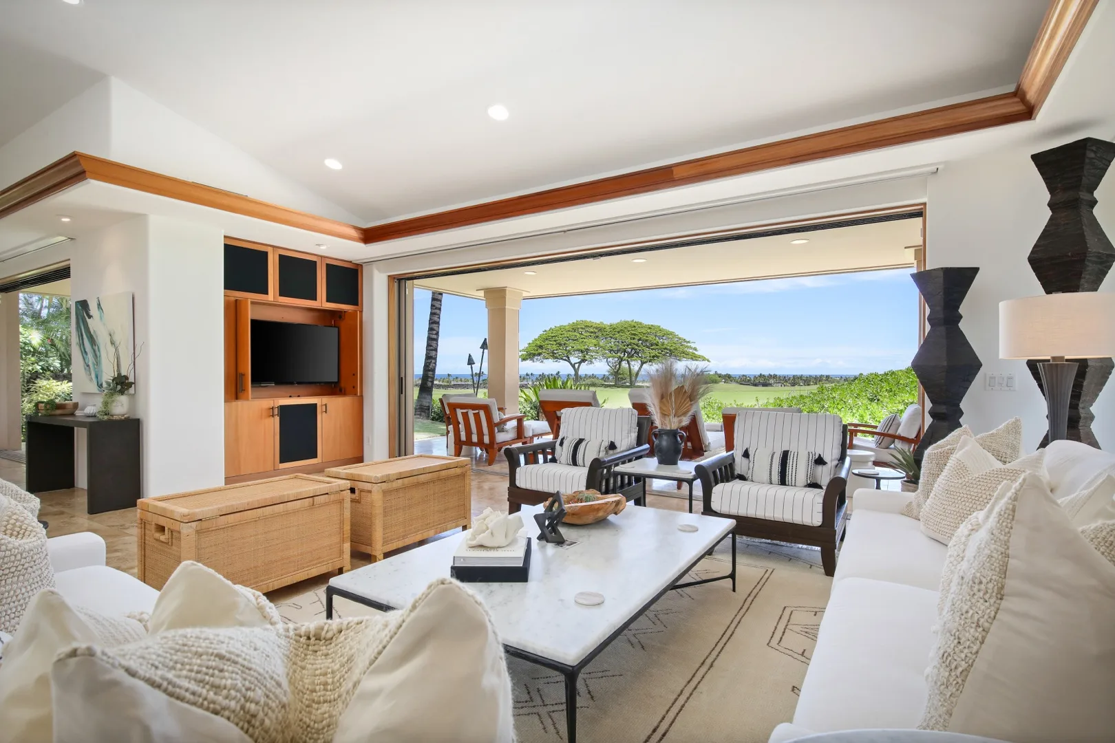 A bright living room opens onto a patio, with seating arranged around a coffee table.