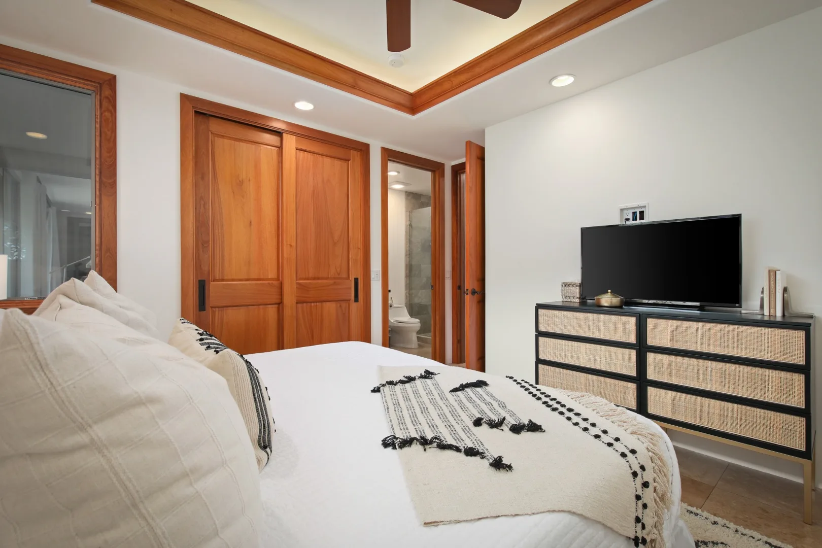 A bedroom with a bed, wooden closet doors, and a television on a low cabinet.