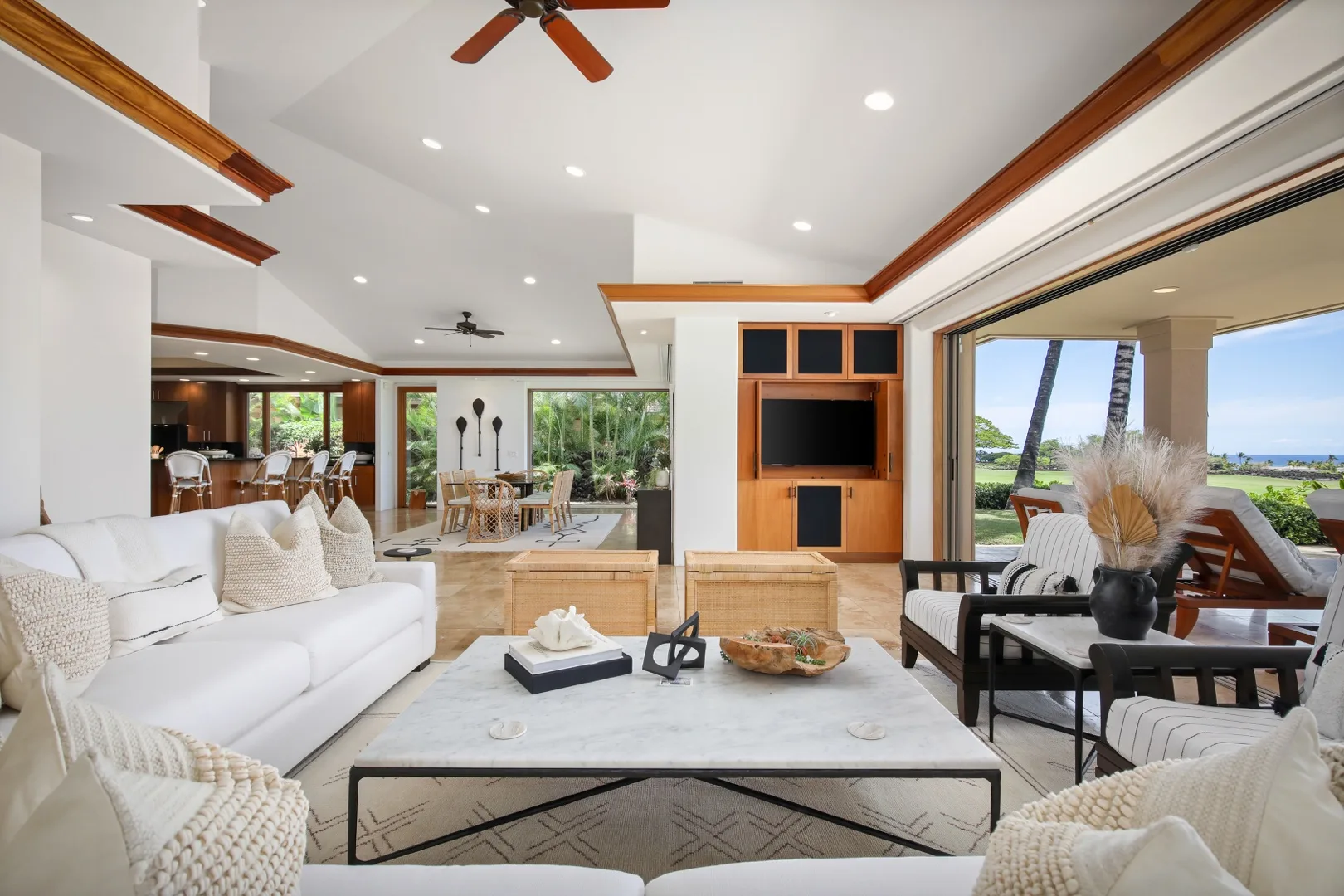 A bright living room opens onto a dining area and a patio with views outside.